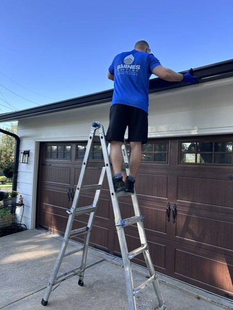 Barnes crew installing a new gutter over a garage